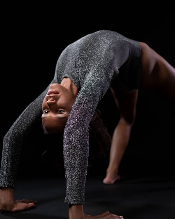 Woman in a calm yoga pose in a modern, dark studio.